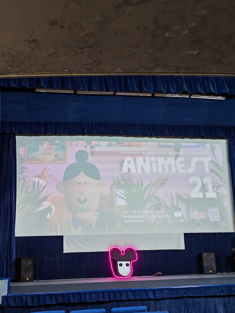Panou de proiecție pentru Festivalul Internațional de Film de Animație Animest 21, cu detalii despre dată și locație, pe un fundal decorativ în sala de proiecție.